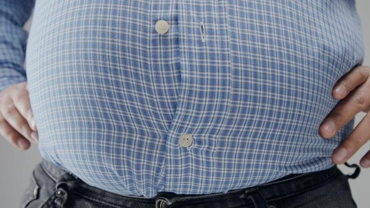 The belly of an overweight man, bursting the buttons of his shirt.